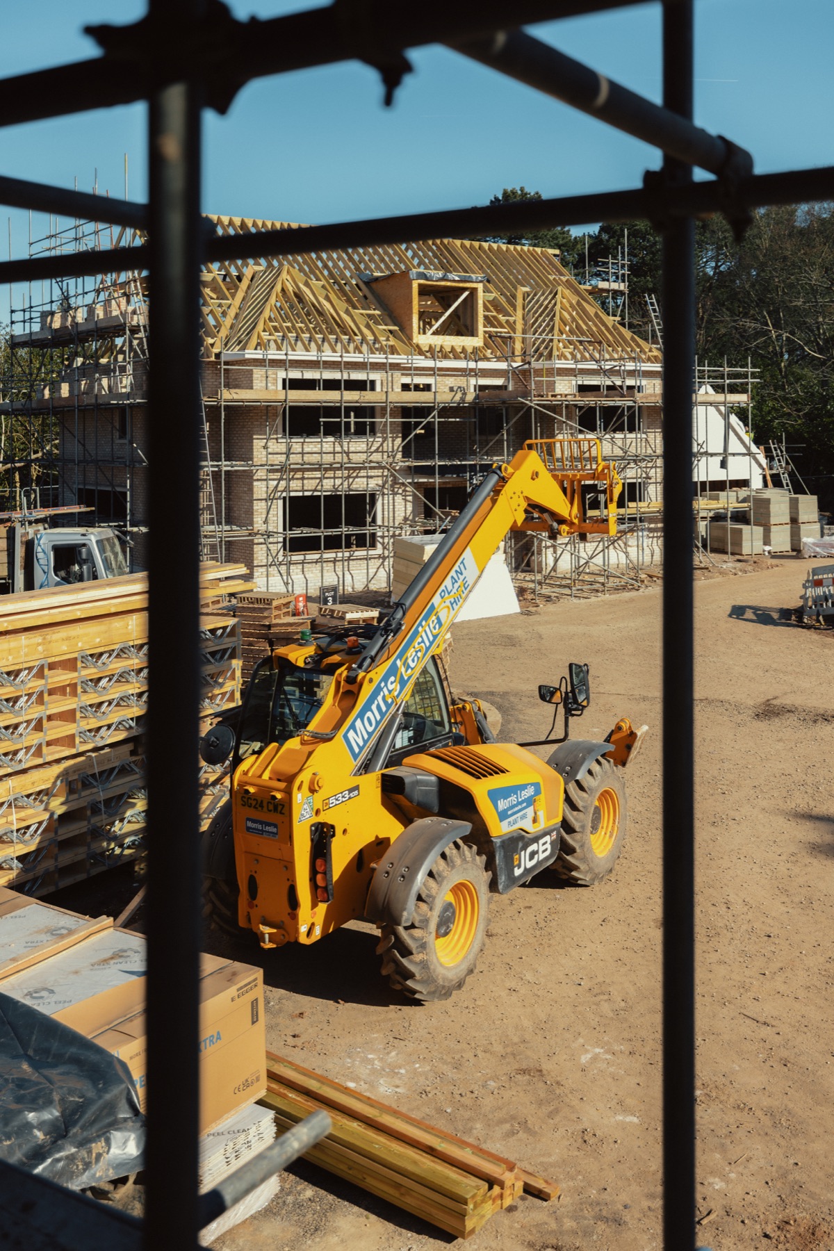 Roof construction and a telehandler at Park View, framed through scaffolding